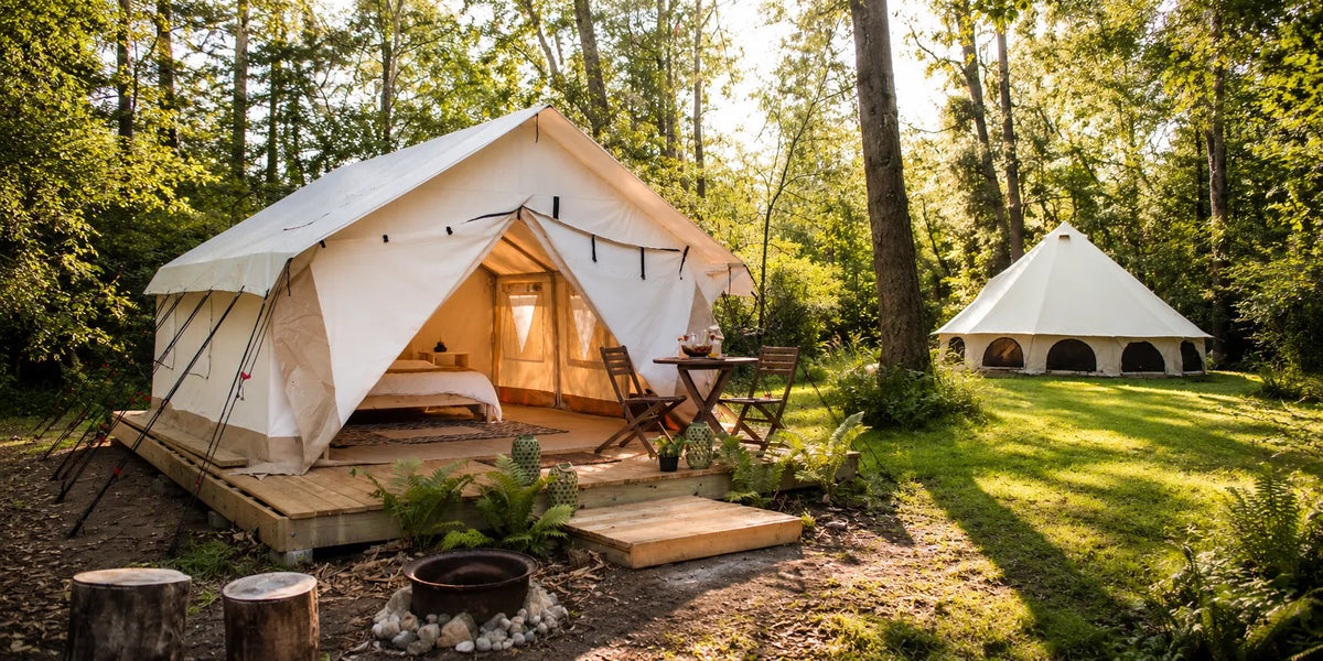 Avalon bell tent and Alpha wall tent luxury glamping setup in a forest clearing with wooden deck, cozy interior, outdoor seating, and warm natural sunlight in a premium camping scene.