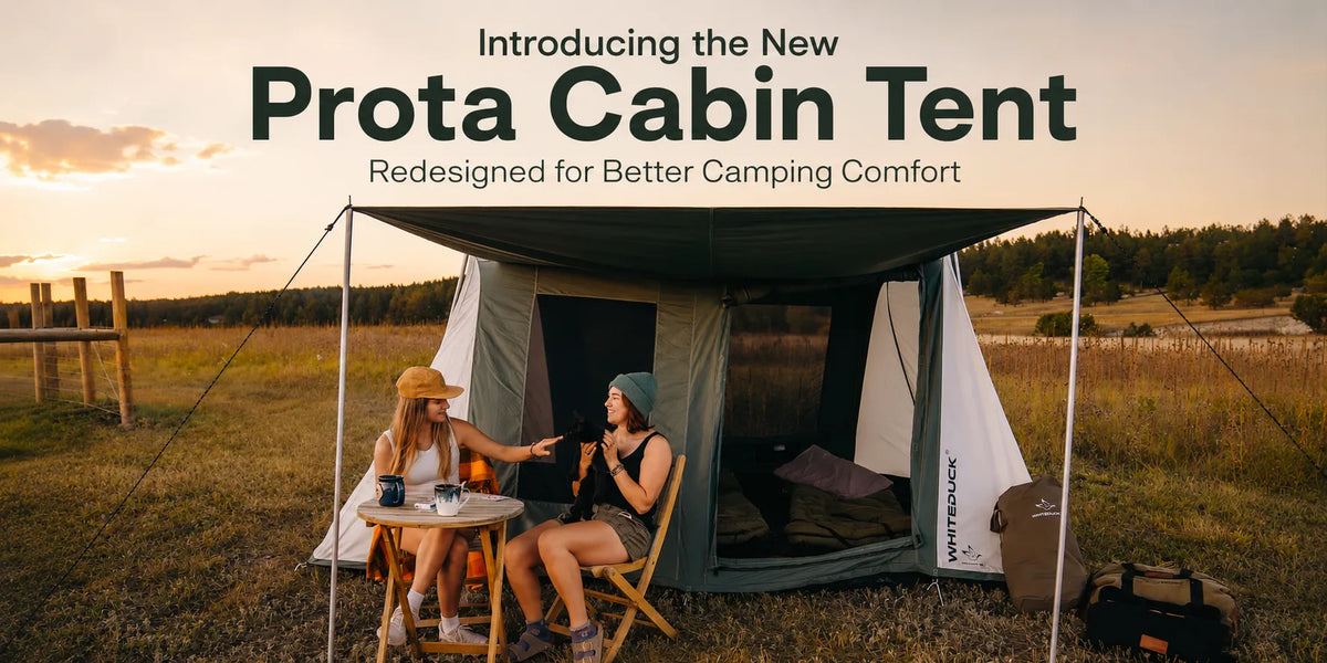 Two women relaxing outside the new Prota Cabin Tent by White Duck Outdoors during golden hour, showcasing the redesigned cabin tent for enhanced camping comfort.