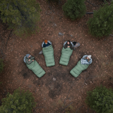 Four people lying in sleeping bags in a forest